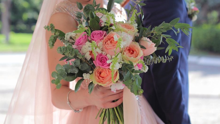 Bride holding a beautiful bridal bouquet. Wedding bouquet of peach roses by David Austin,  single-head pink rose aqua, eucalyptus, ruscus, gypsophila