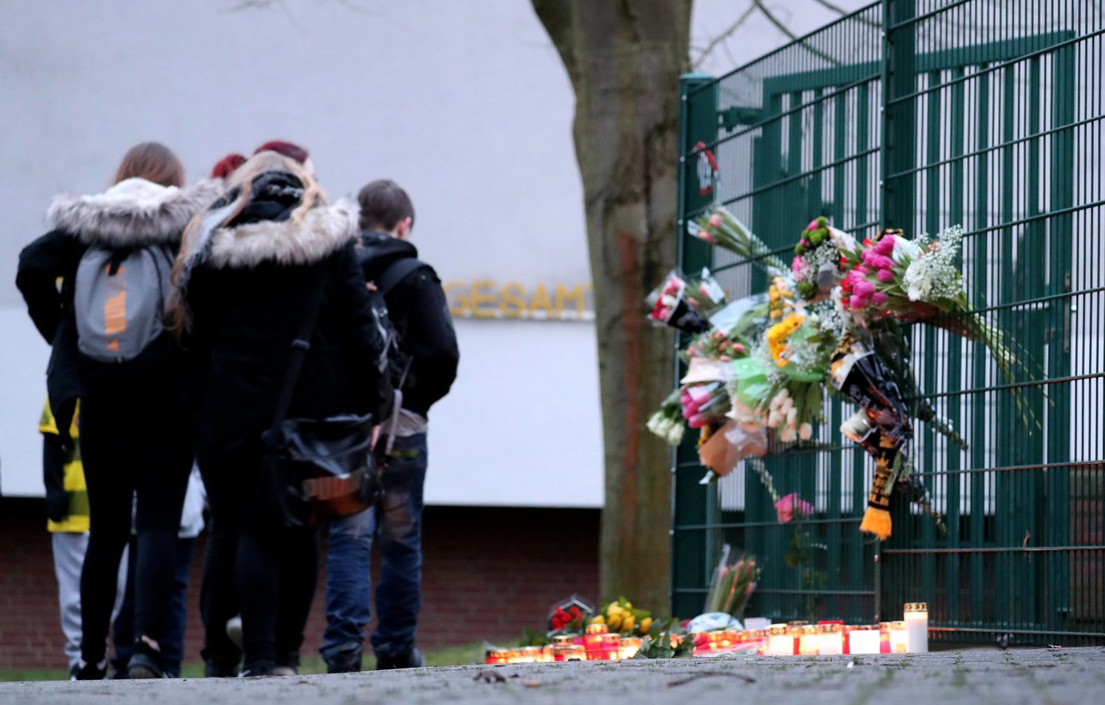 Przed szkołą koledzy zamordowanego ucznia ustawili znicze, a na ogrodzeniu umieścili wiązanki kwiatów