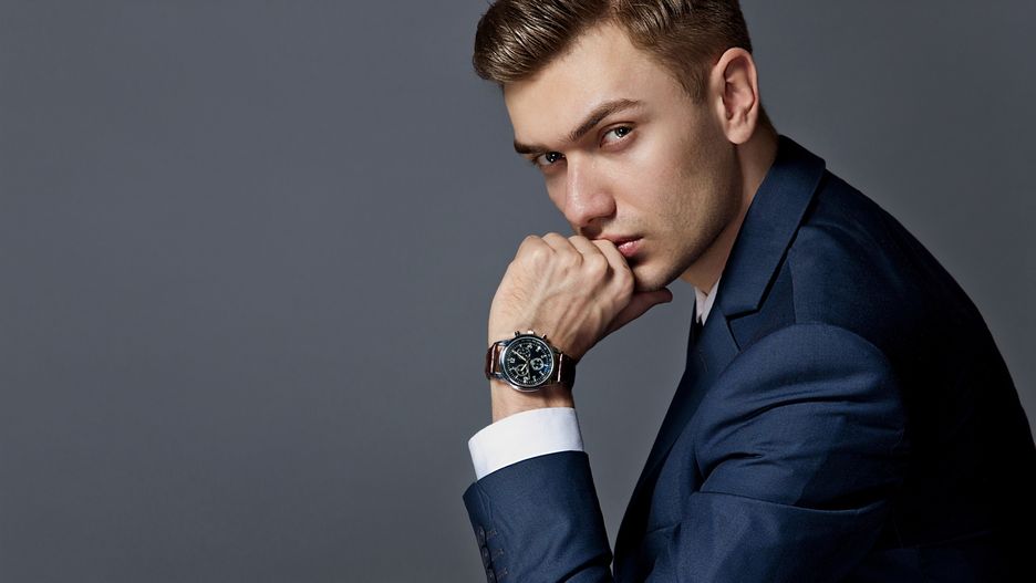 man in an expensive suit in a tie and an expensive watch posing in the studio