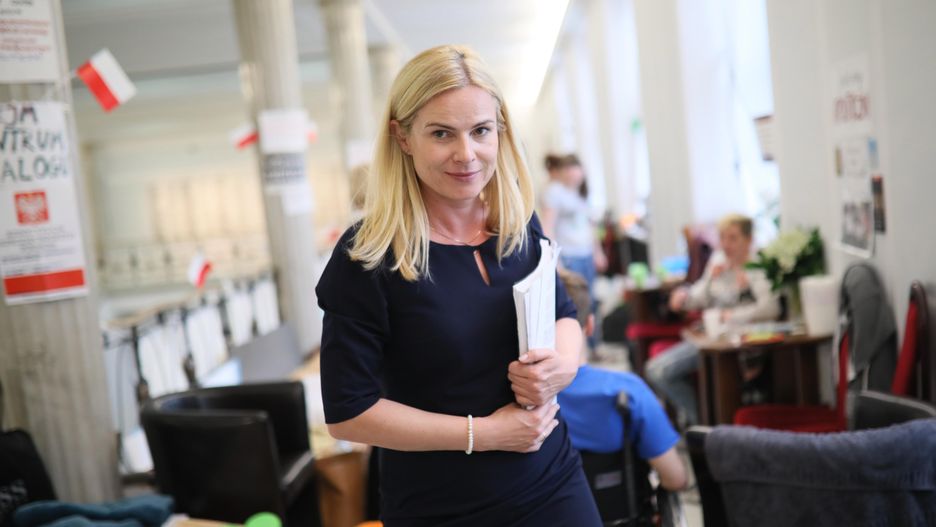 Była posłanka Nowoczesnej Joanna Schmidt w Sejmie. W tle protestujący opiekunowie i osoby niepełnosprawne