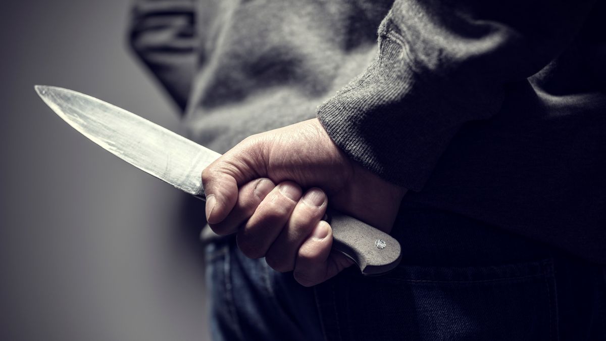 Criminal with knife weapon hidden behind his back