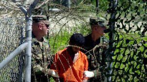 Amerykańscy żołnierze prowadzą jednego z osadzonych w Guantanamo