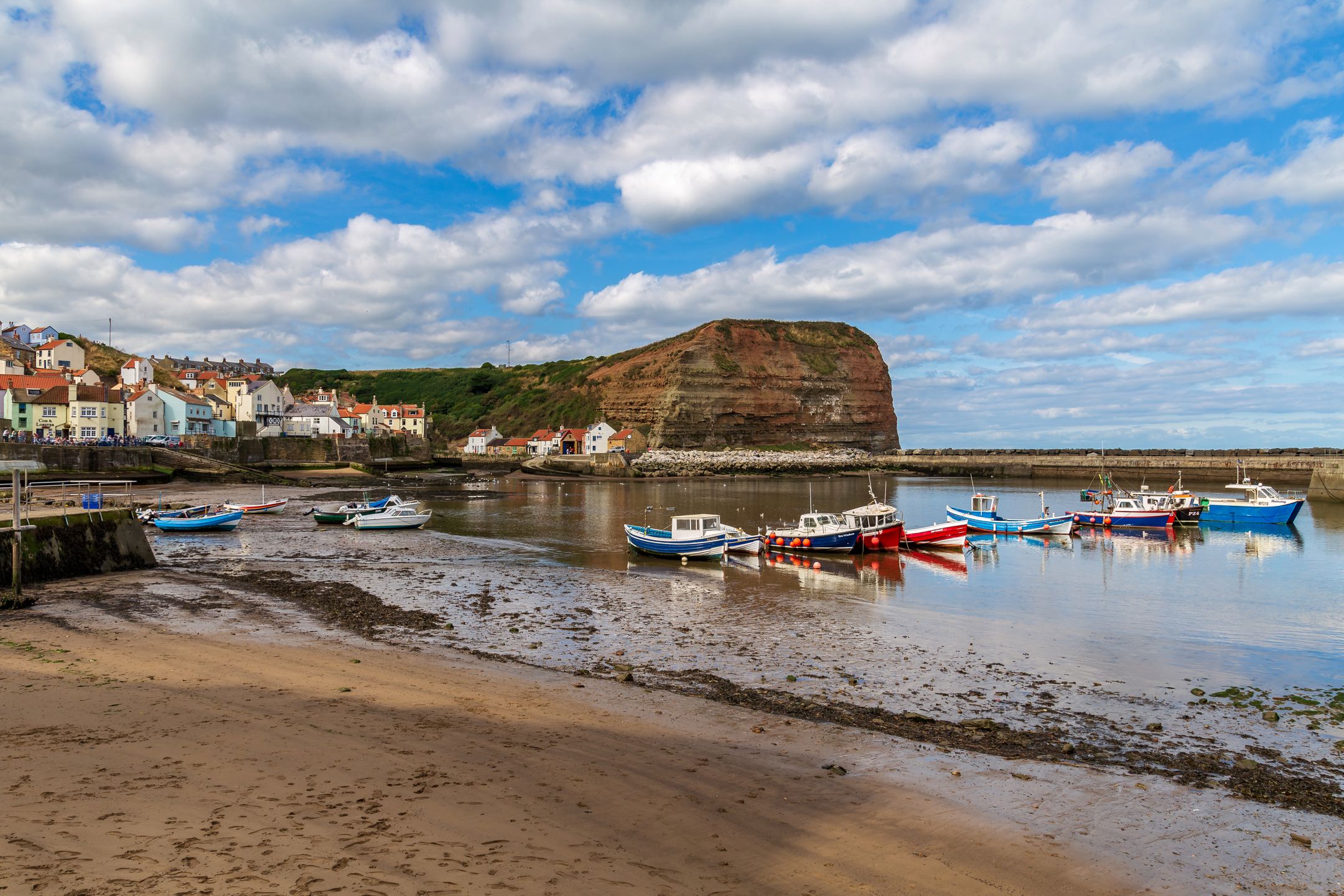 Staithes, North Yorkshire, England, UK - September 07, 2016: View from the beach towards Staithes Beck and the Lifeboat Station, with some boats on the beach and in the water 