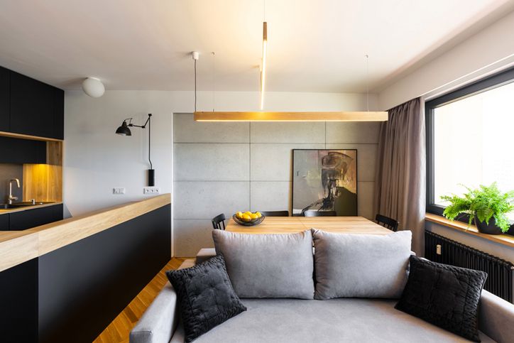Hipster black and gray open space living and dining room interior with a stylish sofa and a concrete wall 