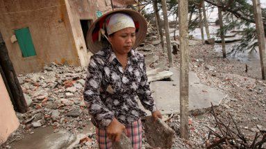 Kobieta usuwa gruz z domu zniszczonego po przejściu tajfunu Damrey