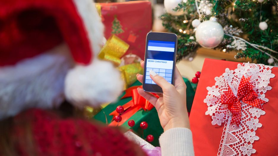 Woman using smart phone and typing Merry Christmas text message. Christmas wishes on cell phone.