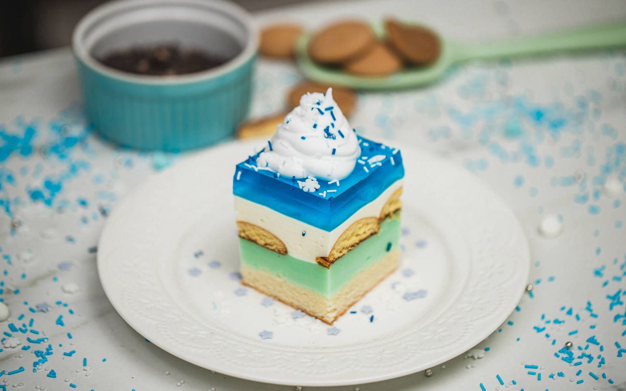 Ciasto Królowa Śniegu na biszkopcie z kolorowymi kremami i niebieską galaretką