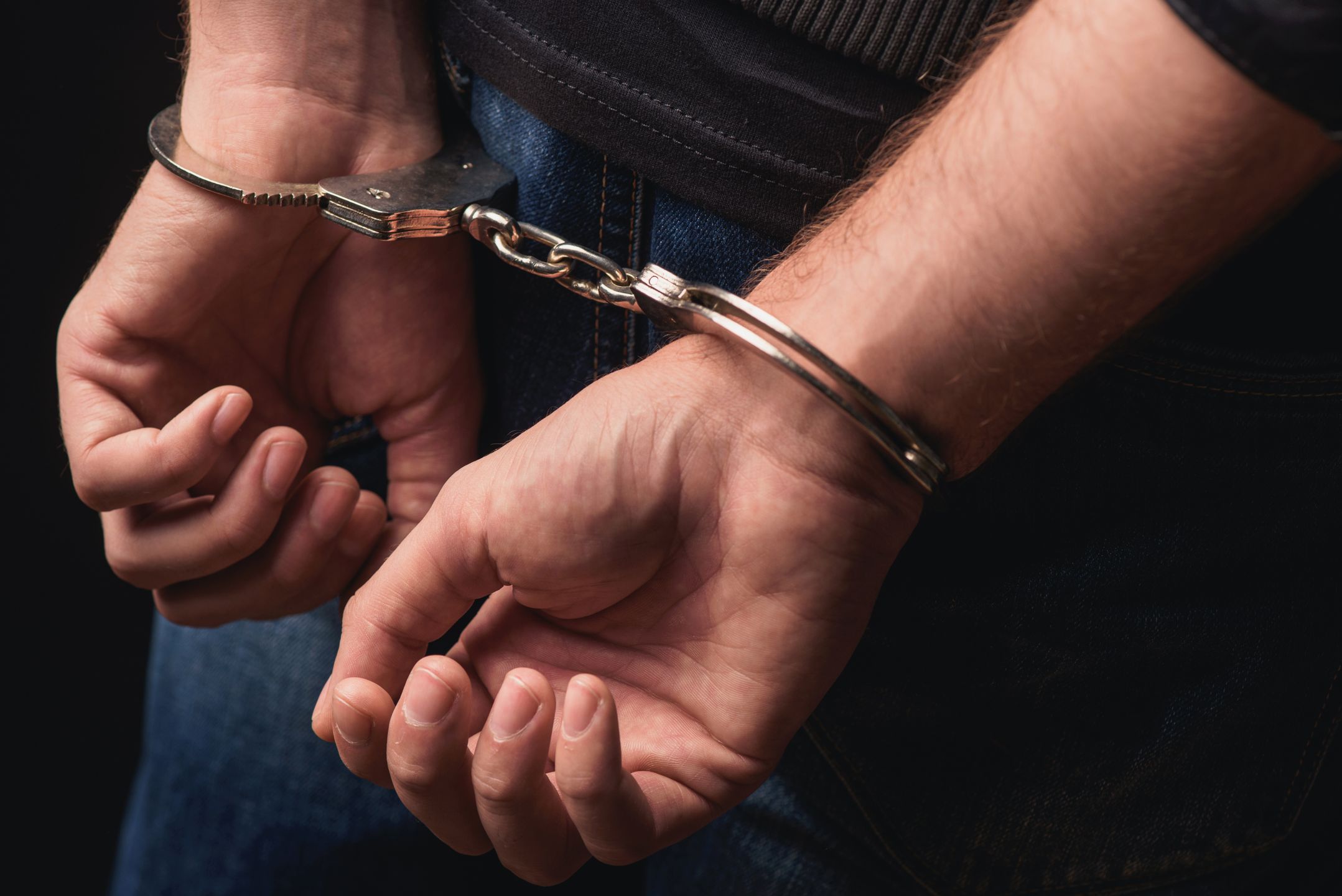 Close up of male hands in bracelets behind back