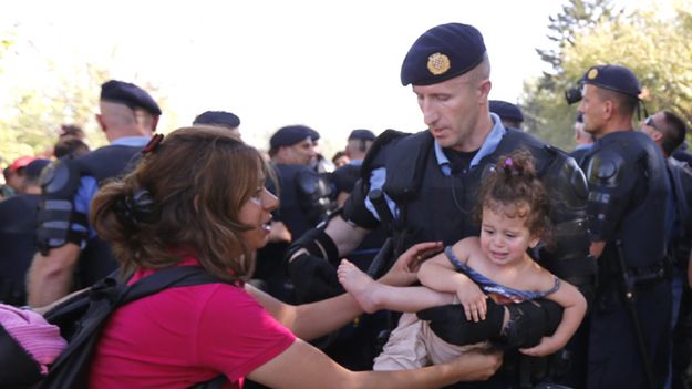 Chorwacki policjant zabiera dziecko uchodźczyni do obozu dla uchodźców nieopodal miasta Tovarnik