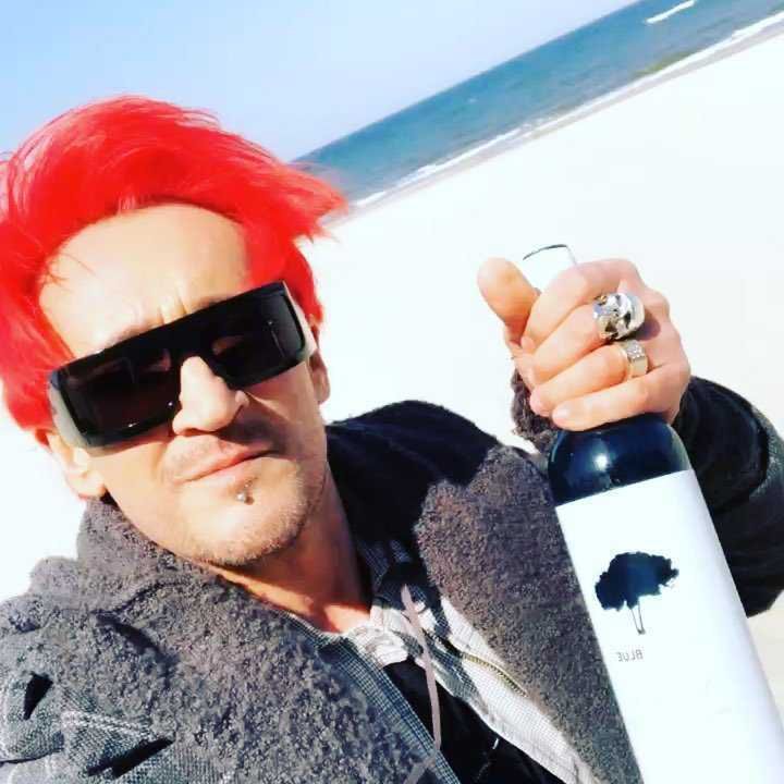 Michał Wiśniewski pije wino na plaży na planie nowego teledysku