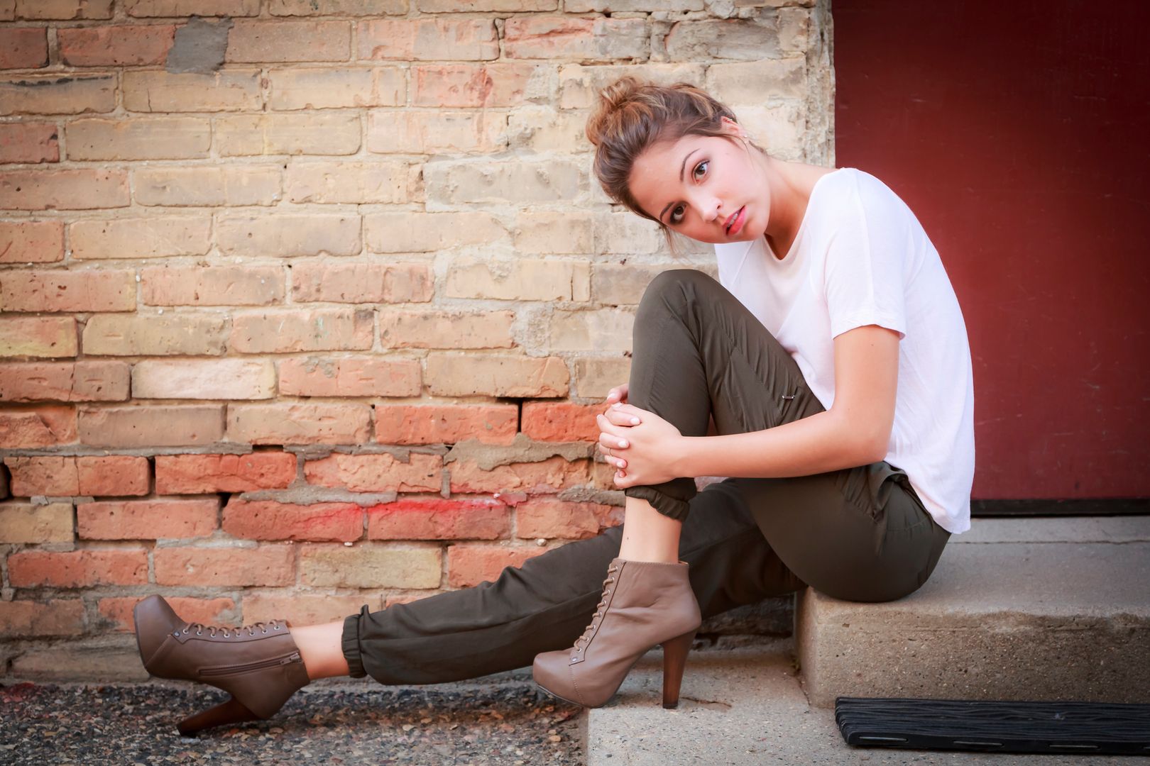 Portrait of a beautiful woman sitting on the steps by a brick wall. 