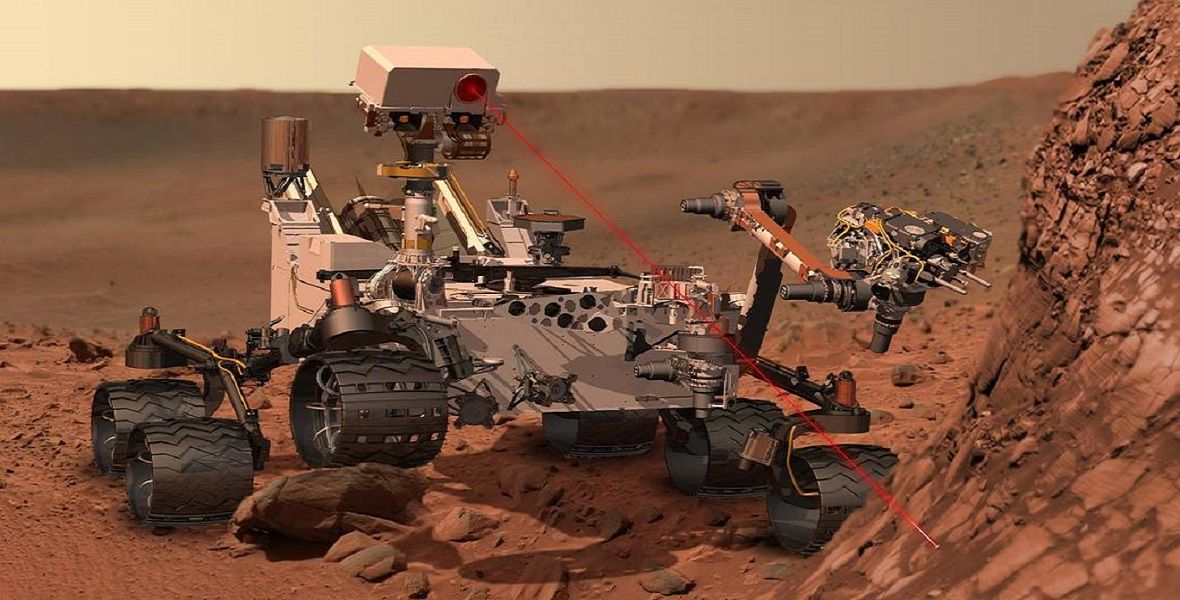 Łazik Curiosity na Marsie. W rzeczywistości laser nie jest widocznym, ale dla celów ilustracyjnych pokazano go jako widoczne czerwone światło. 