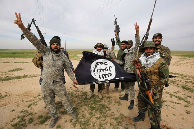 Bojownicy pozujący z flagą ISIS
