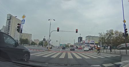 Rowerzysta przejeżdża przez ruchliwe skrzyżowanie na czerwonym świetle
