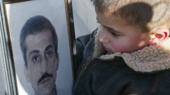 Chłopiec trzyma zdjęcie ojca, który zginął w katastrofie