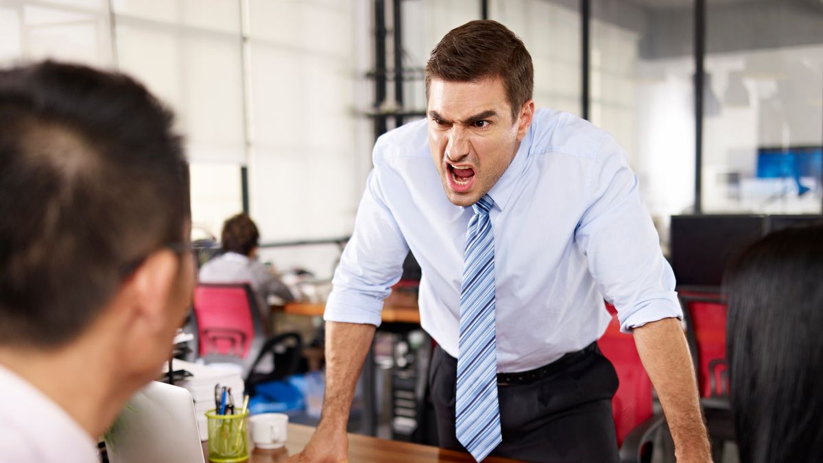 bad-tempered caucasian business executive yelling at two asian subordinates in office.