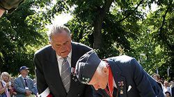 Powstańcy zapalają znicz przed pomnikiem