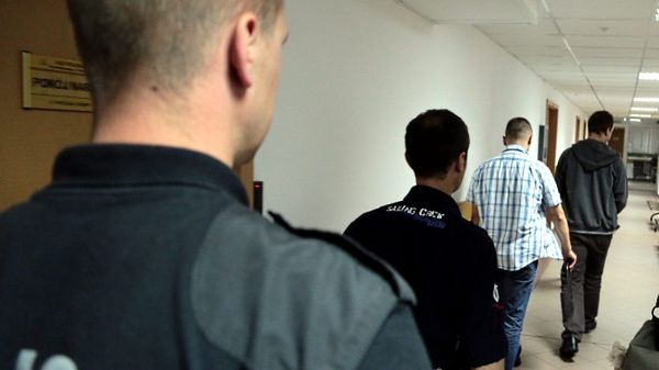 Policjanci prowadzą na salę rozpraw w Sądzie Rejonowym dla Warszawy Śródmieścia jednego z zatrzymanych kibiców