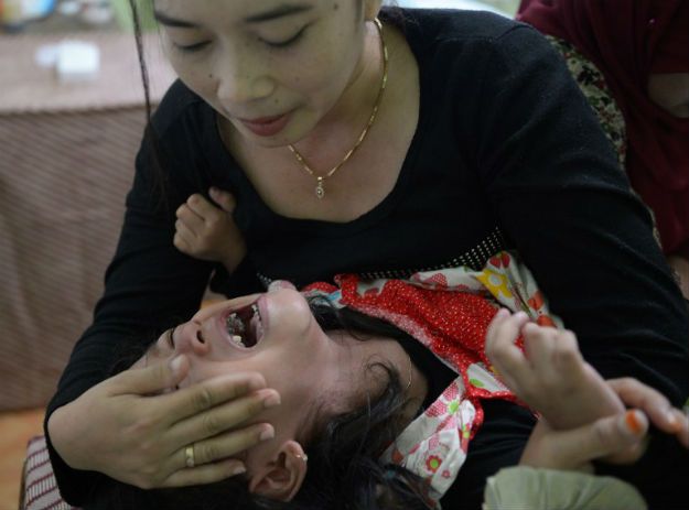 Indonezyjka próbuje uspokoić 4-letnią córkę, którą poddała zabiegowi obrzezania