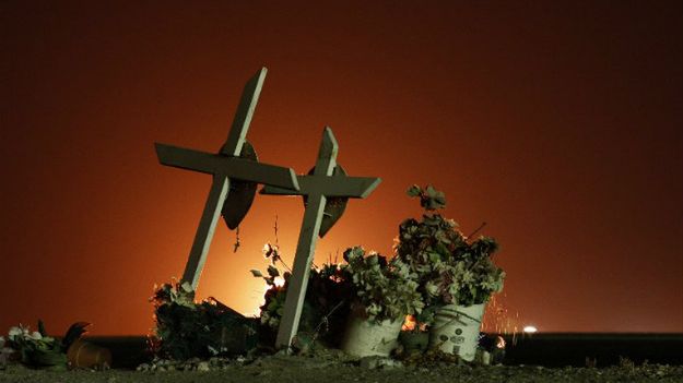 Krzyże przydrożne w Buttonwillow w Kalifornii na tle łun ognia z pól ropy łupkowej