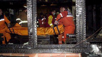 Strażacy wynoszą ze zgliszczy ciało jednej z dziewięciu ofiar