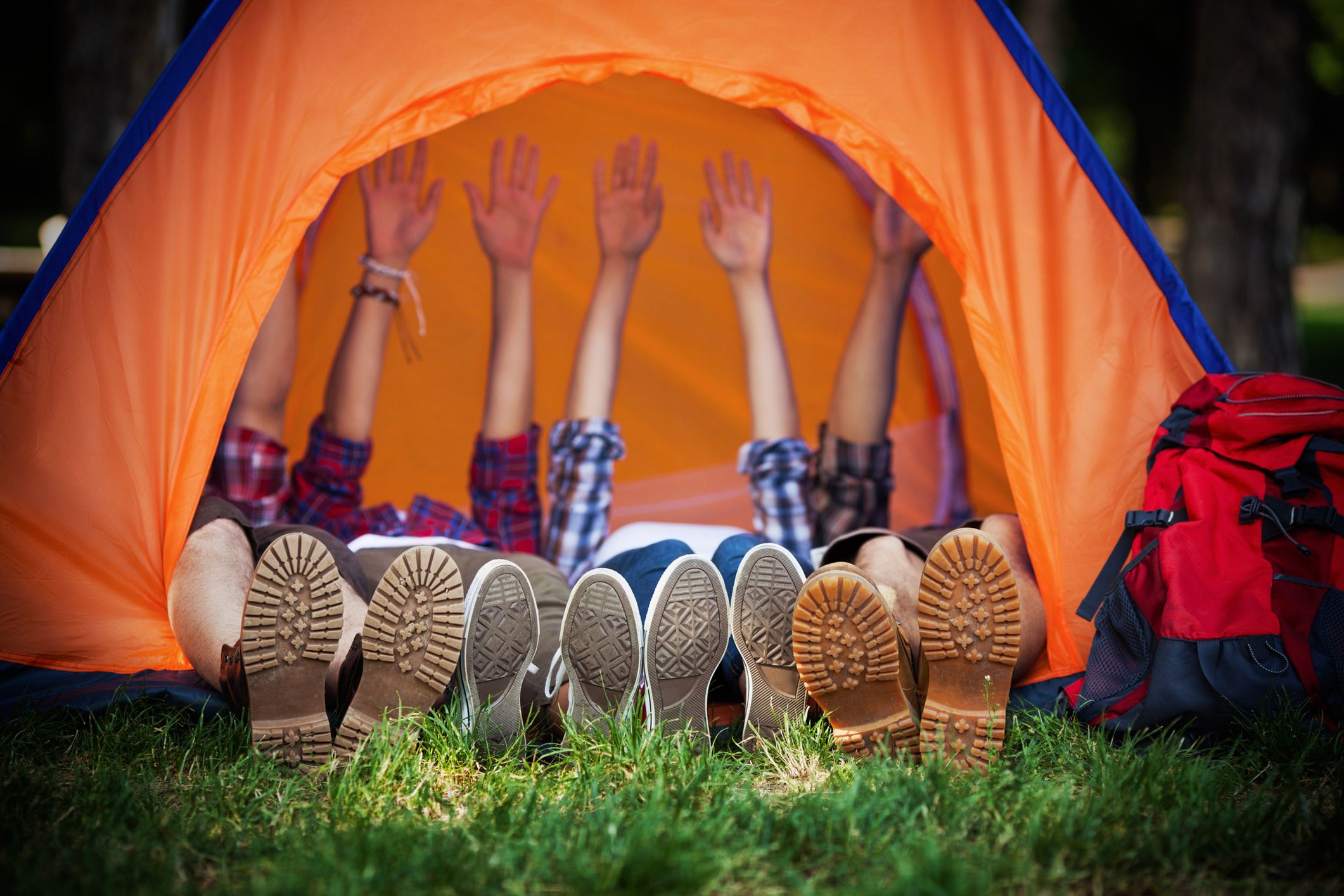 Group of young campres lying down in a tent with their hands up 