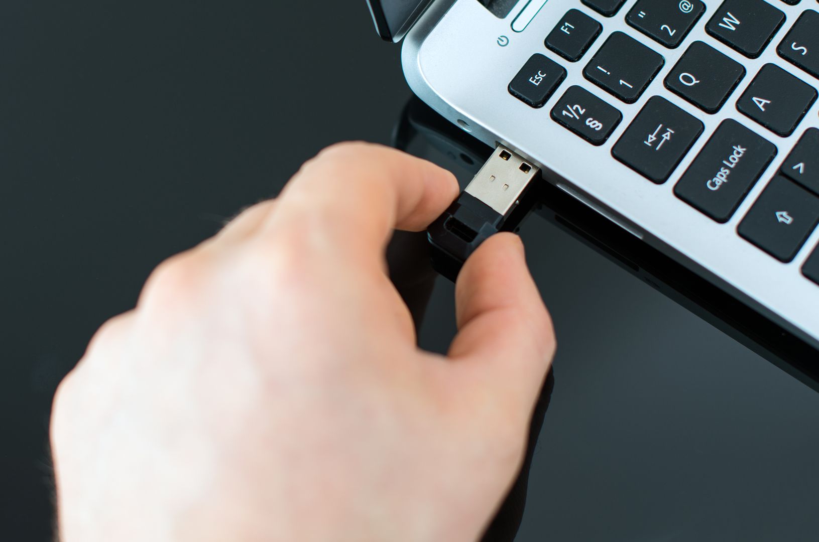 Hand plugging usb flash drive to laptop.