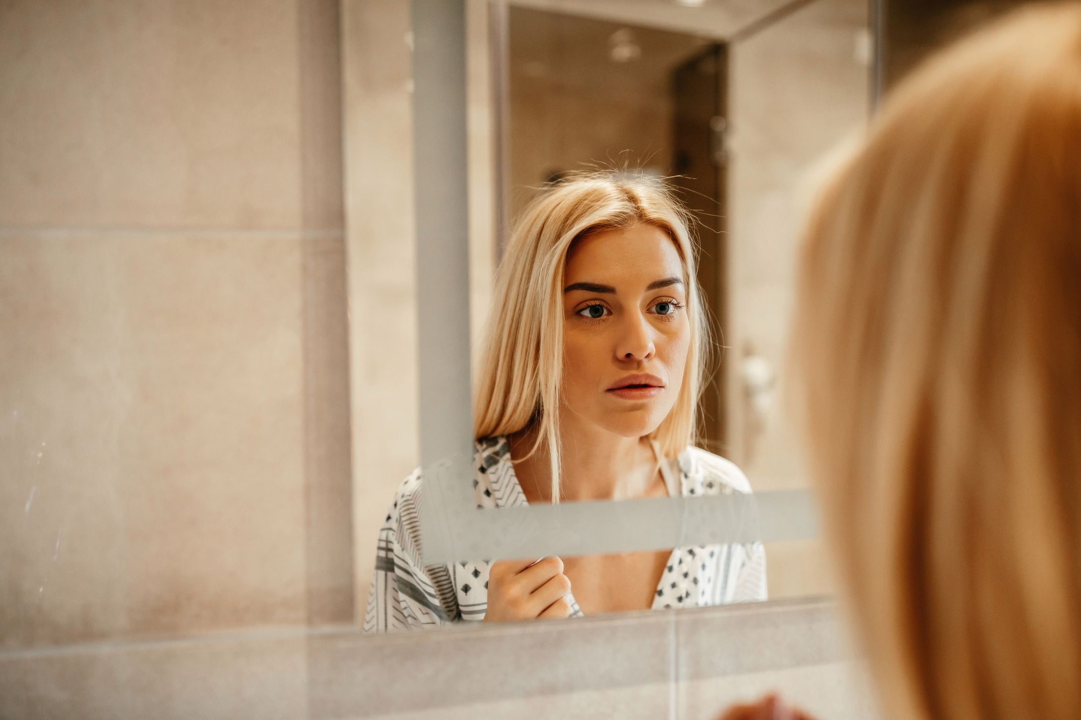 Attractive young woman standing in front of the mirror 