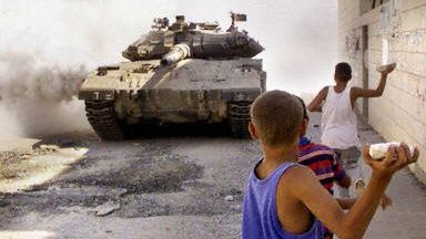 Palestyński chłopiec obrzuca kamieniami izraelski czołg