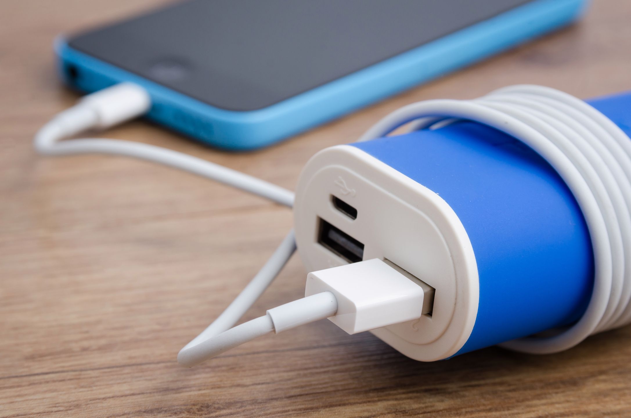 Charging a smartphone from powerbank on wooden table 