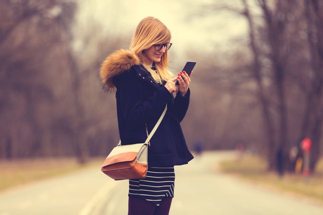 Cute woman texting on her smart phone outdoors. 