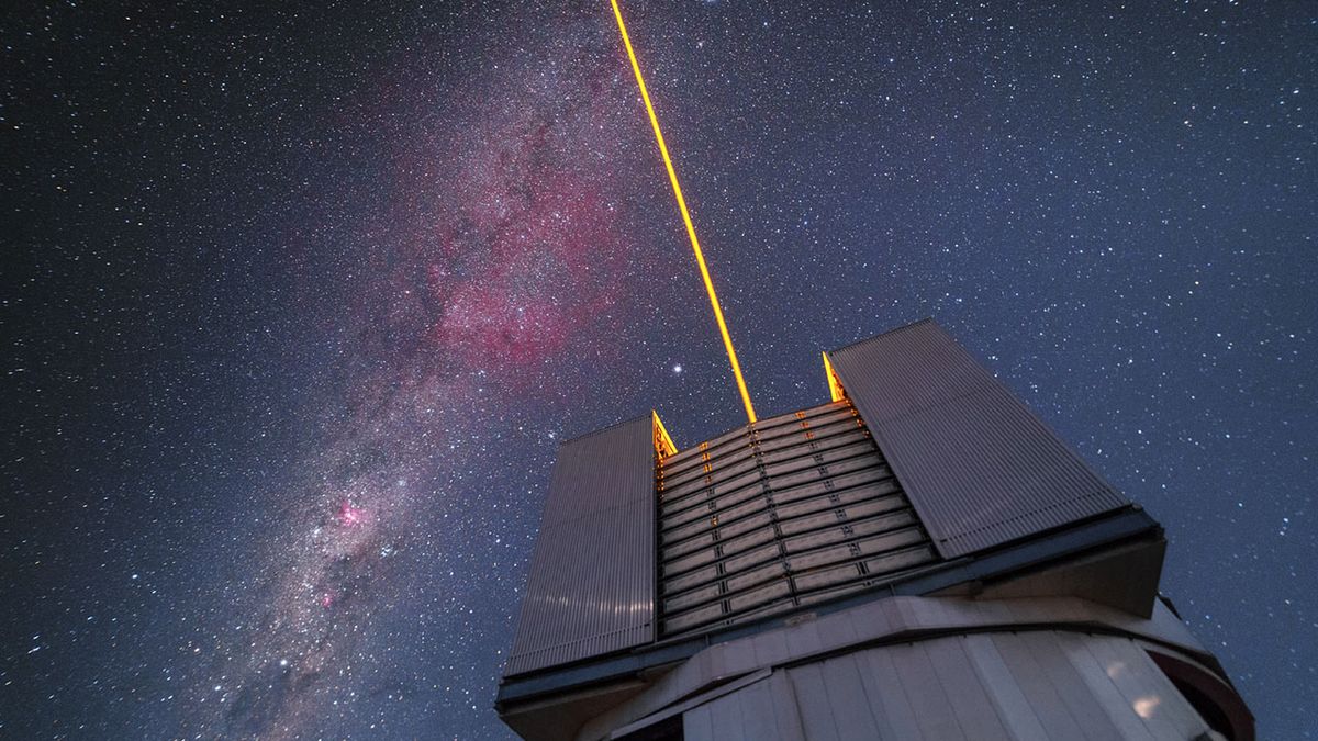 The VLT issue a laser into the sky over Paranal. The beam functions as an artificial star and is used to correct for atmospheric disturbance. The southern Milky Way crosses the sky, featuring the constellation of Carina among others.