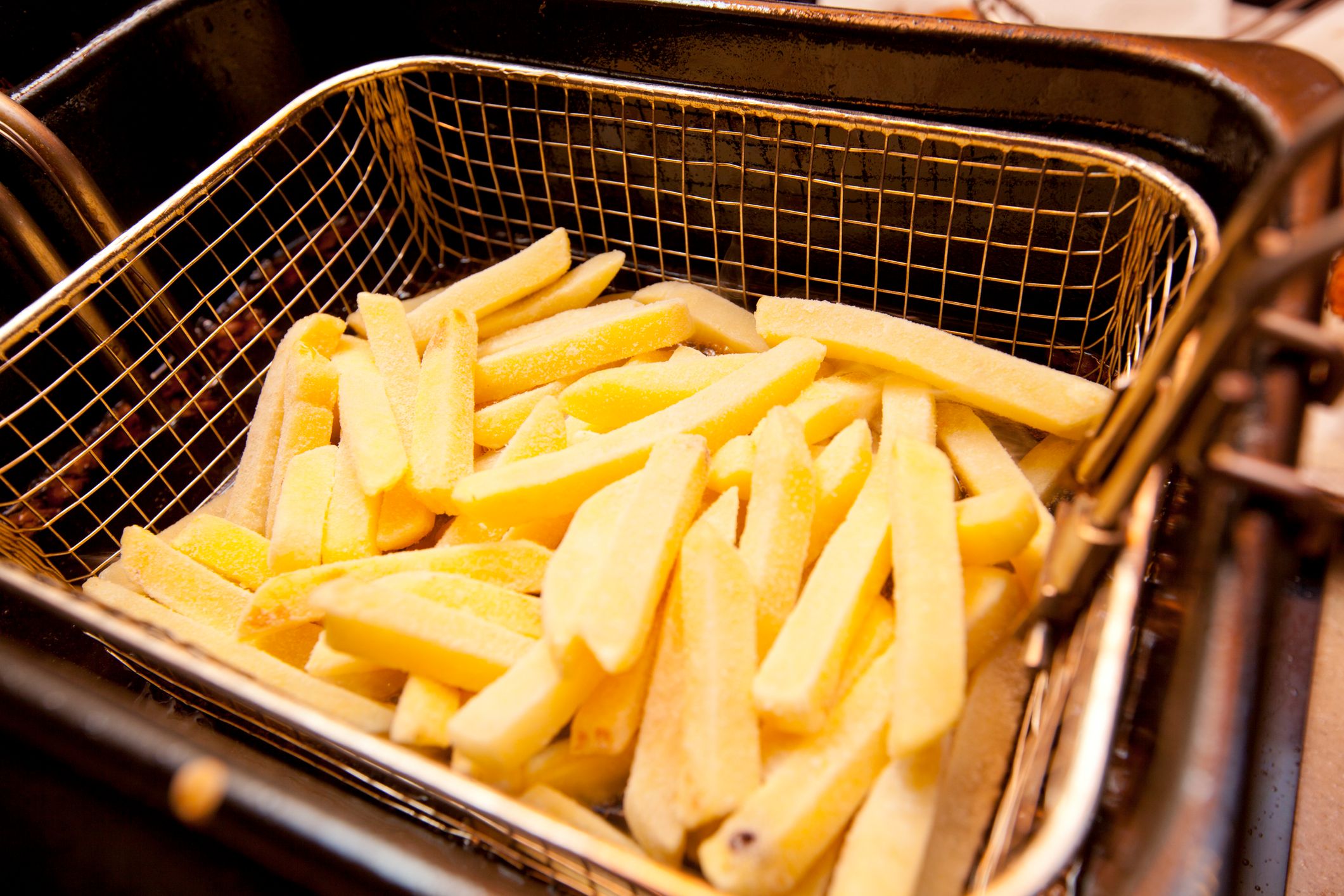 Cooking french fries in a deep fryer basket. 
