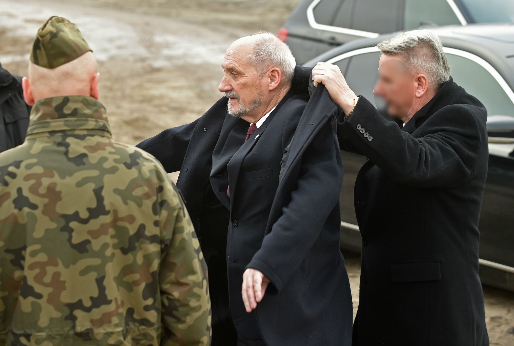 Antoni Macierewicz zakłada płaszcz. Nie sam. Ma od tego ludzi