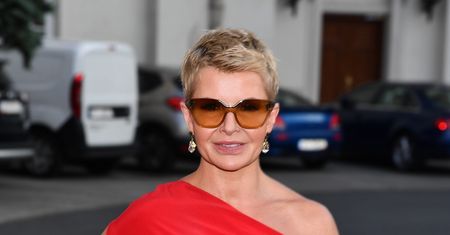 Joanna Racewicz cała w czerwieni. Jej twarz nie wyraża żadnych emocji