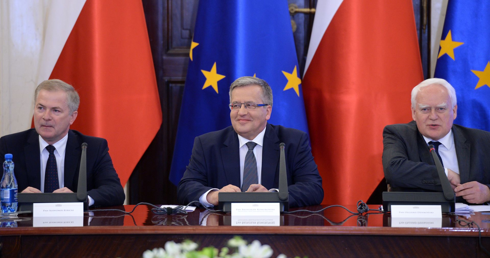 Sławomir Rybicki, Bronisław Komorowski i Olgierd Dziekoński. Najbliżsi współpracownicy byłego prezydenta. W tle flagi Unii Europejskiej.