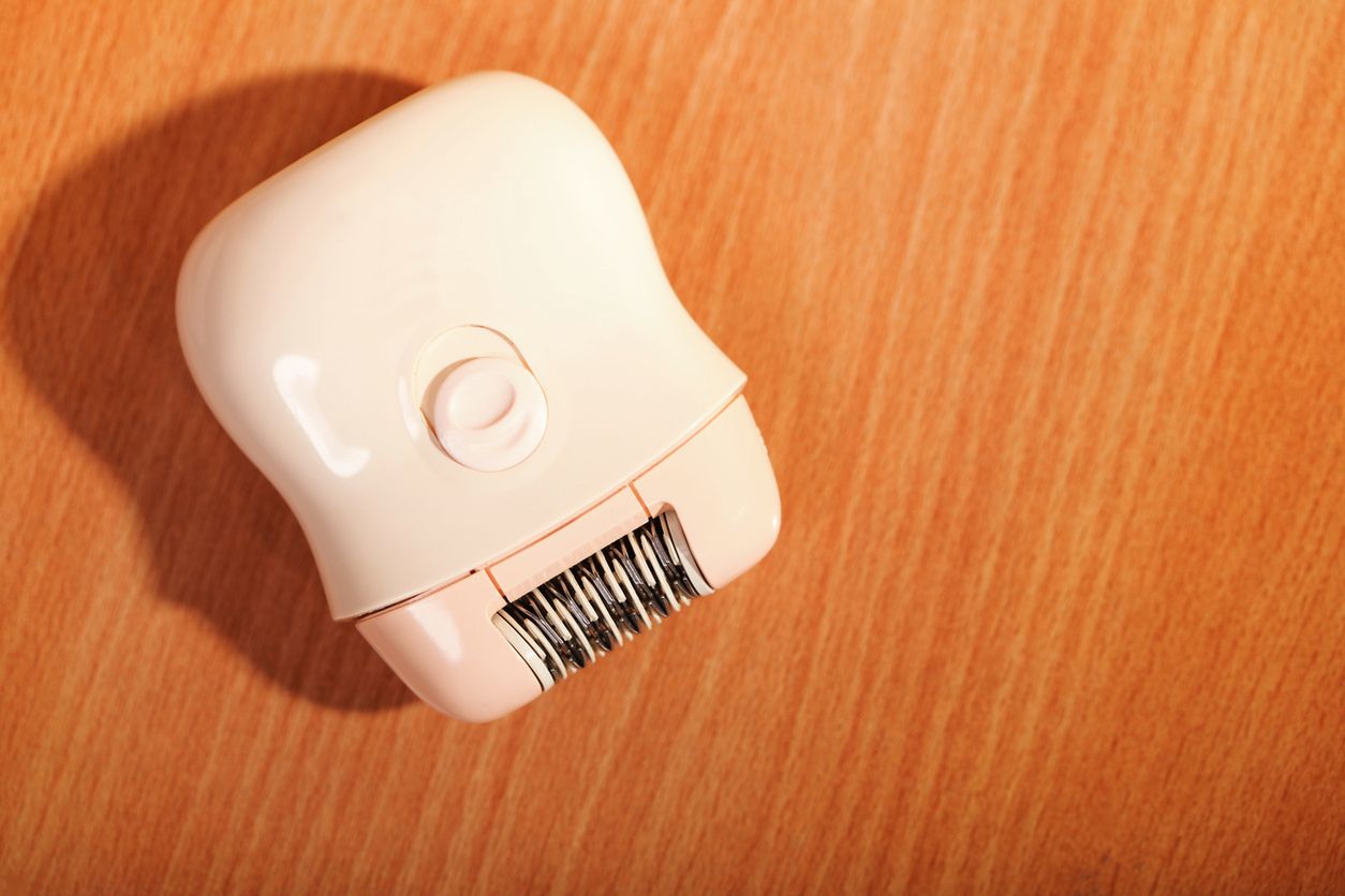Ladies electric hair remover shaver depilator on wooden table. Beauty and skin body care concept 