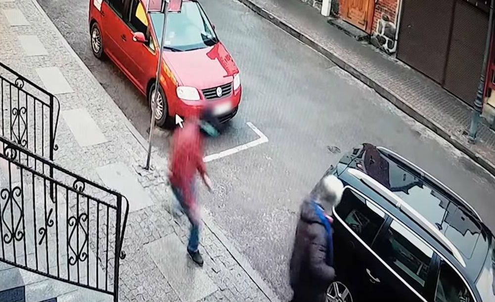 Napastnik (w czerwonej kurtce) atakuje wychodzącego z kantoru przedsiębiorcę