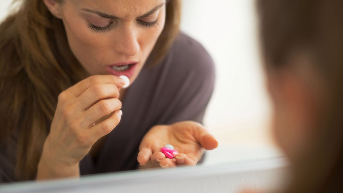 Kobieta połyka tabletki