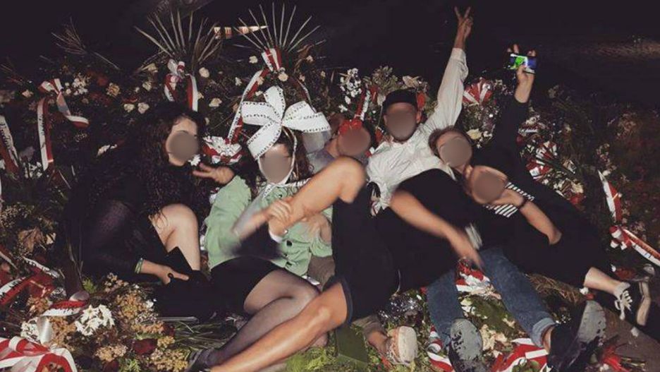 Grupa młodych ludzi sfotografowała się na wieńcach pod pomnikiem rotmistrza Pileckiego.
