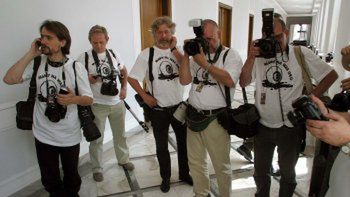 Fotoreporterzy w białych koszulkach z napisem "Mamy na Was oko" w Sejmie