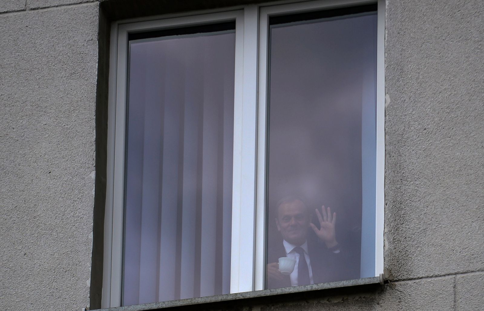 Donald Tusk jak papież. Były premier pozdrawia z okna zgromadzonych przed prokuraturą
