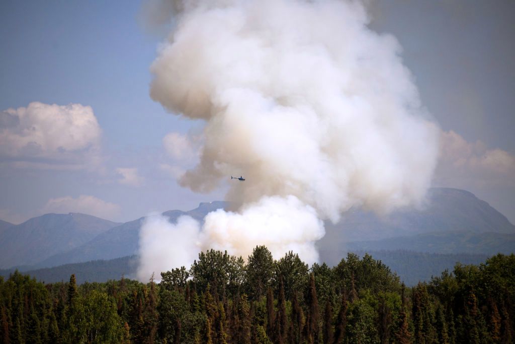TALKEETNA, AK - JULY 03: A helicopter passes by as smoke rises from a wildfire on July 3, 2019 south of Talkeetna, Alaska near the Gorge Parks Highway. Alaska is bracing for a dangerous fire season with record warm temperatures and dry conditions in parts of the state. (Photo by Lance King/Getty Images)