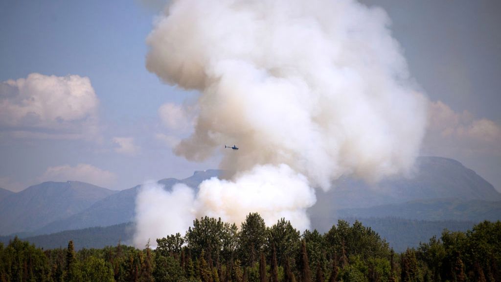 TALKEETNA, AK - JULY 03: A helicopter passes by as smoke rises from a wildfire on July 3, 2019 south of Talkeetna, Alaska near the Gorge Parks Highway. Alaska is bracing for a dangerous fire season with record warm temperatures and dry conditions in parts of the state. (Photo by Lance King/Getty Images)