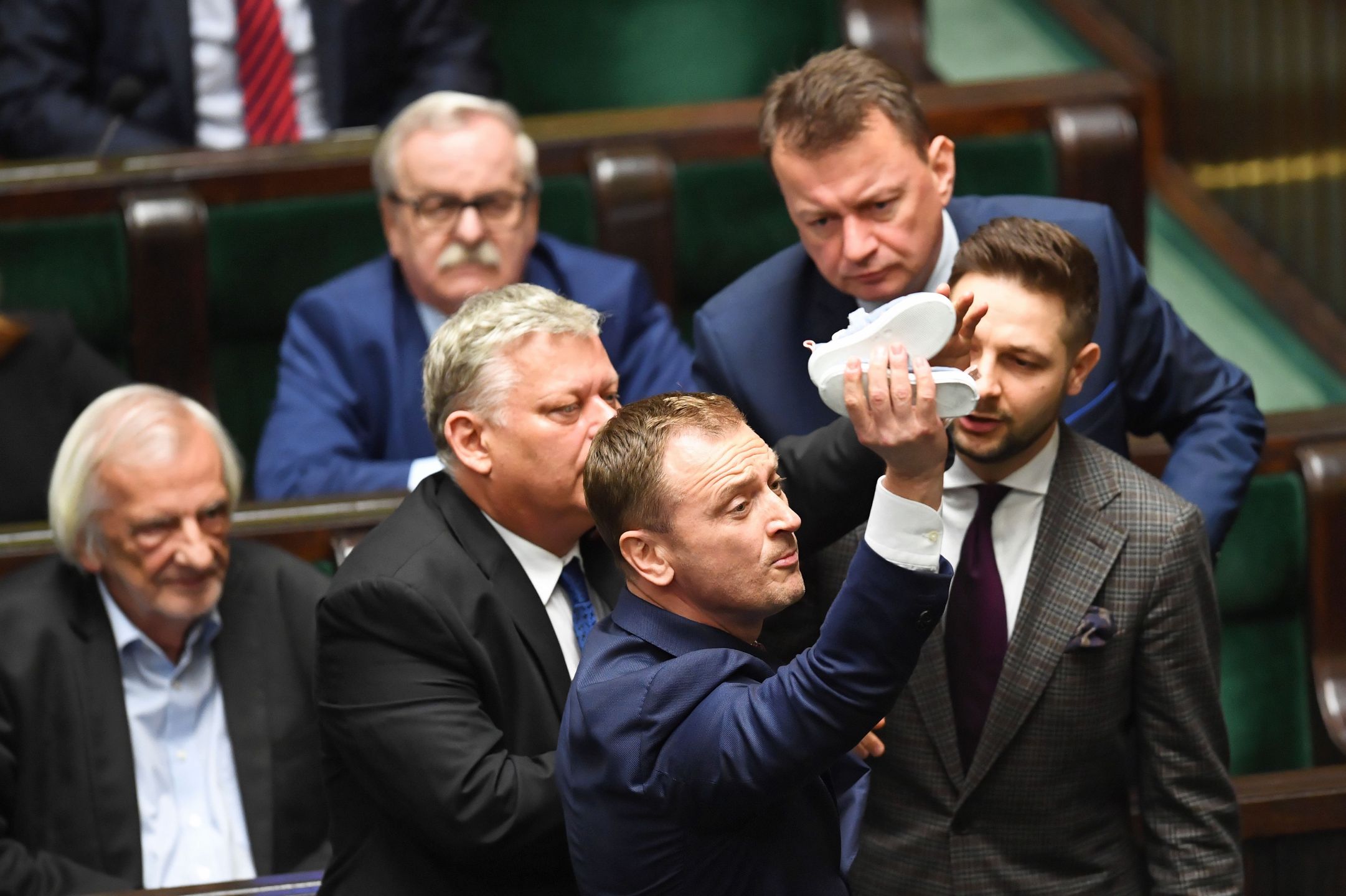 Posiedzenie Sejmu. 16 maja 2019 roku. Poseł PO Sławomir Nitras usiłuje wręczyć dziecięce buciki Jarosławowi Kaczyńskiemu.