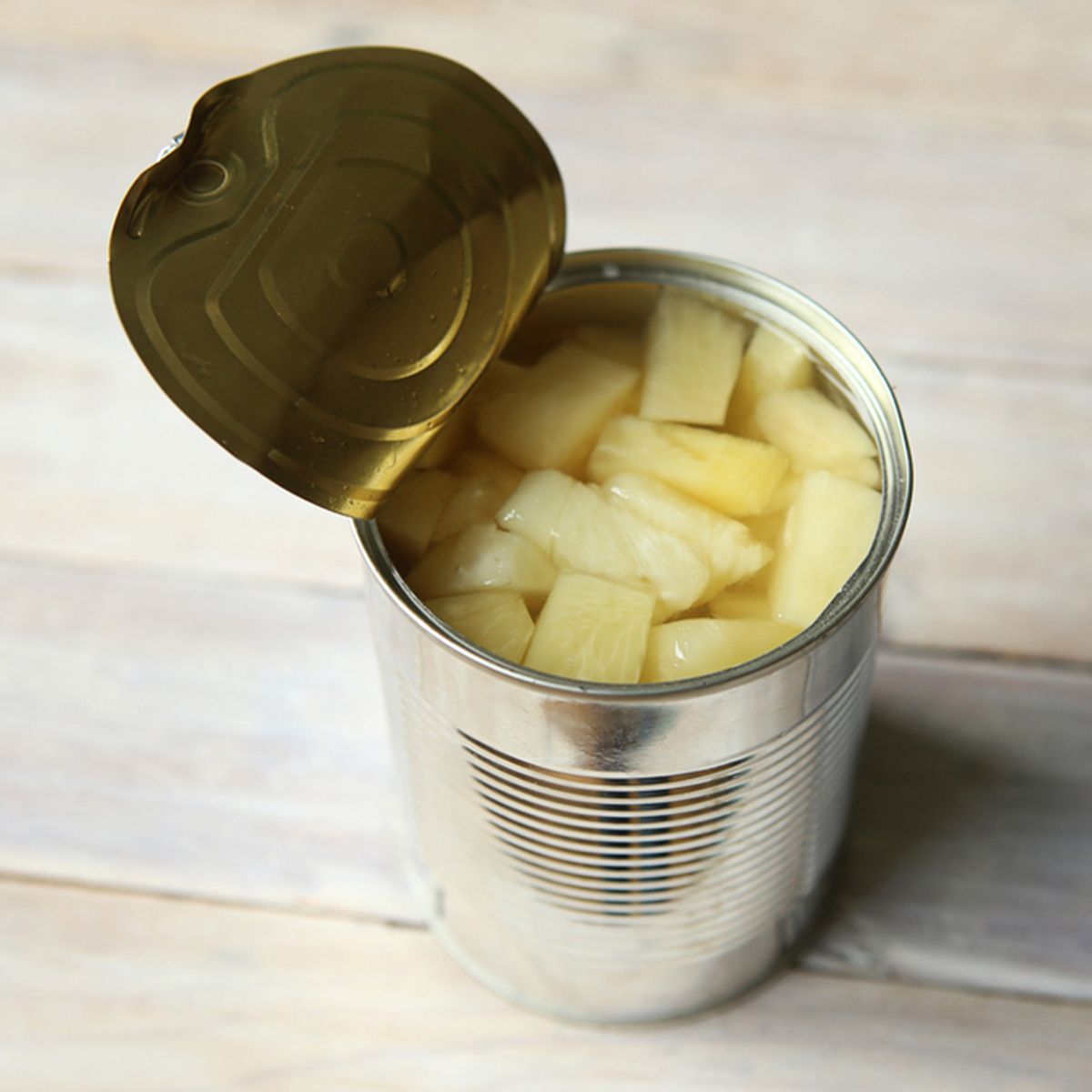 Opened tin can of canned pineapple pieces. Canned pineapple in can on wooden table.; Shutterstock ID 709601191; Job (TFH, TOH, RD, BNB, CWM, CM): TOH