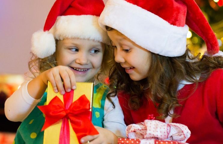 Dziewczynki otwierają świąteczne prezenty.