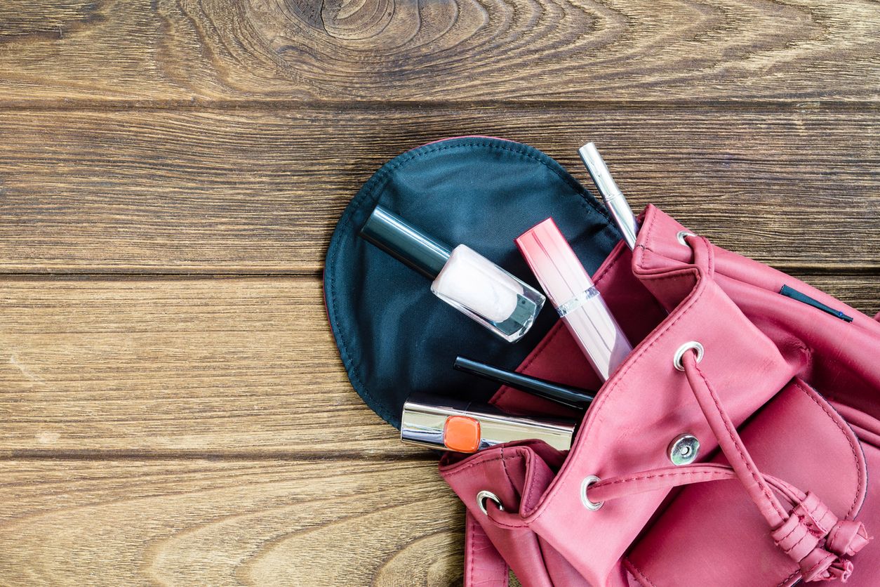 Top view of women bag stuff female cosmetic accessories on wooden texture background 