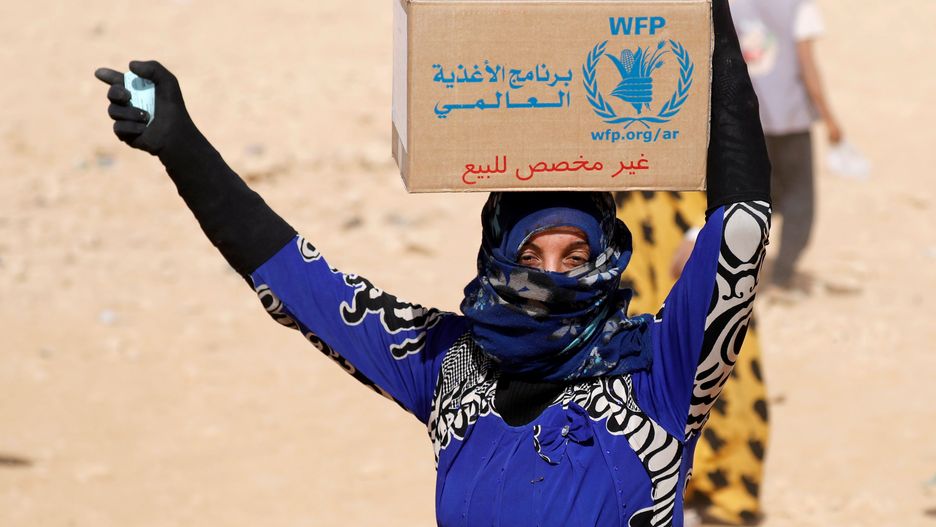 Syryjka z kartonem pomocy żywnościowej w obozie uchodźców