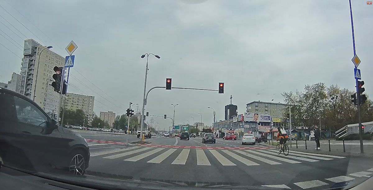 Rowerzysta przejeżdża przez ruchliwe skrzyżowanie na czerwonym świetle